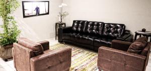 a living room with a leather couch and two chairs at Hotel Galeria in Jales