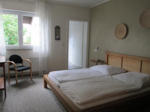 a bedroom with a bed and a chair and a window at Pension Haus Waldfeucht in Waldfeucht