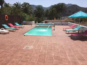 una piscina con tumbonas y sombrilla en Casa Rural Tadia, en San Bartolomé