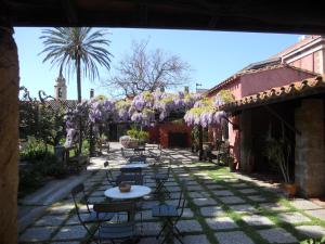 een binnenplaats met tafels en stoelen en paarse bloemen bij Hotel Lucrezia in Riola Sardo