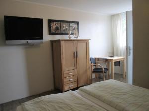a bedroom with a bed and a tv and a desk at Pension Haus Waldfeucht in Waldfeucht