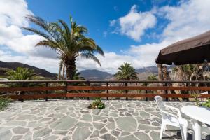 eine Terrasse mit einem Tisch, Stühlen und Palmen in der Unterkunft Country House Lomito De Taidia in Risco Blanco