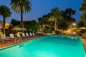 a pool with chairs and palm trees at night at El Pueblo Inn in Sonoma