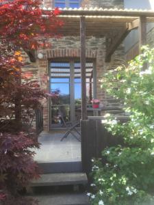 Casa de piedra con puerta de cristal y porche en Le gîte de la vieille église, en Tenneville