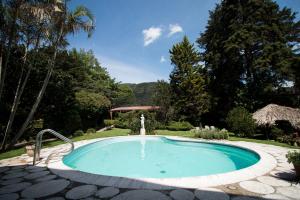 a swimming pool in a garden with a fountain at Cabaña Suiza in Guatemala +20 photos