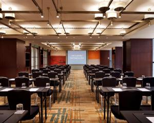 une salle avec des tables, des chaises et un écran de projection dans l'établissement Hyatt Regency Jinan, à Jinan