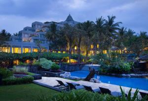 a hotel with chairs and a pool in front of a building at Hyatt Regency Yogyakarta in Yogyakarta