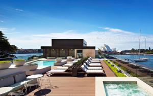 a rooftop patio with a swimming pool and the sydney opera house at Park Hyatt Sydney in Sydney