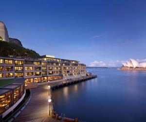 een groot gebouw met 's nachts verlichting op het water bij Park Hyatt Sydney in Sydney