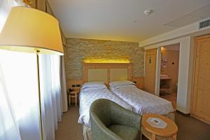 Habitación de hotel con cama y silla en Hotel Ladina, en Campitello di Fassa