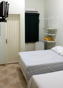 1 Schlafzimmer mit 2 Betten, einem TV und einem Schrank in der Unterkunft Pousada Sertão Veredas in Sao Domingos de Goias