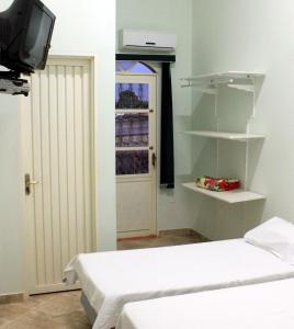 um quarto com duas camas e uma televisão e uma porta em Pousada Sertão Veredas em Sao Domingos de Goias