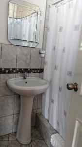 y baño con lavabo, espejo y ducha. en Residencial Carlos, en Lima