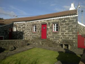 a stone house with a red door and a yard at Casas do Monte Alegre in Nordestinho