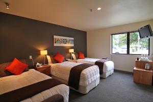 a hotel room with two beds and a flat screen tv at Drifters Inn in Hanmer Springs