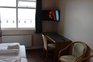 a room with a desk and a tv on the wall at North Star Hotel Olafsvik in Ólafsvík