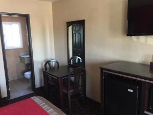 a room with a table and a mirror and a bathroom at Harbor Inn & Suites Oceanside in Oceanside