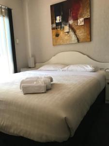 a white bed with a towel on top of it at Mollymook Paradise Haven Motel in Mollymook