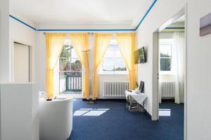 a room with yellow curtains and a desk and a mirror at Hotel am Wind in Großenbrode +35 photos