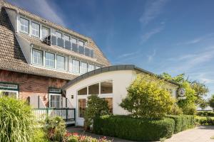 a brick house with a balcony and bushes at Hotel am Wind in Großenbrode