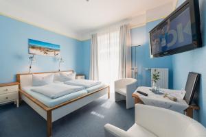 a hotel room with a bed and a flat screen tv at Hotel am Wind in Großenbrode