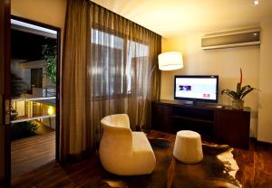 危地馬拉的住宿－拉因馬庫拉達酒店，客厅配有两把白色椅子和电视