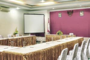 a row of tables in a room with a screen at Hotel Galuh Anindita in Yogyakarta