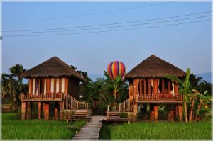 dos chozas en un campo con un globo de aire caliente en ViengTara VangVieng Resort, en Vang Vieng