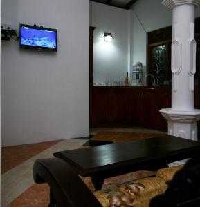 Anjana Villa في غالي: غرفة معيشة مع طاولة وتلفزيون على الحائط