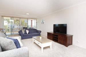 a living room with a couch and a flat screen tv at Sandbar unit 401 in Forster