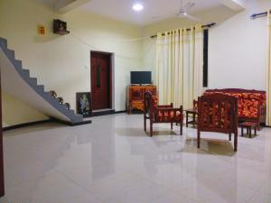 a living room with a bed and chairs and a staircase at Villa Happy Home in Bentota