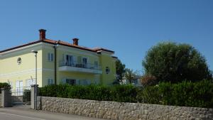 una casa amarilla con una valla delante de ella en Villa Simfonija en Malinska