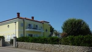 a yellow house with a fence in front of it at Villa Simfonija in Malinska