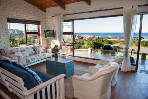 sala de estar con muebles blancos y ventana grande en La Mer Seafront Selfcatering Accommodation Kleinmond, en Kleinmond