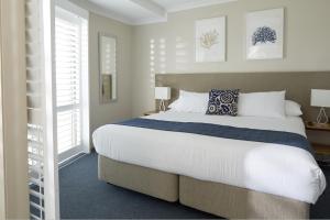 
a white bed sitting in a bedroom next to a window at Seashells Scarborough in Perth
