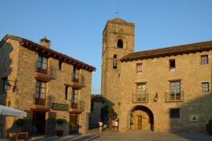 a large stone building with a tower in the background at Apartamentos El Palacete de Ainsa in Aínsa