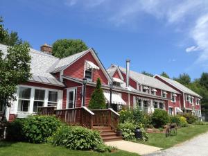 een rood huis met een veranda en een tuin bij The Vermont Inn in Mendon