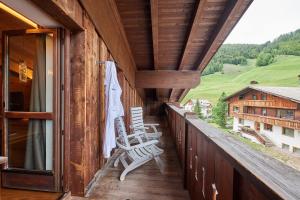 a balcony with two rocking chairs on a house at Sporthotel Panorama in Corvara in Badia