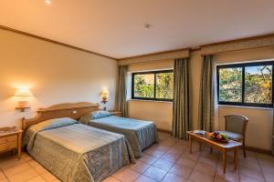 a hotel room with two beds and two windows at Grand Hotel Gozo in Għajnsielem