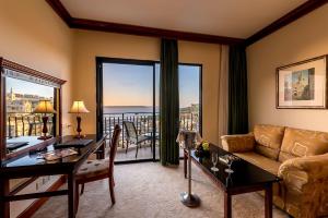 a living room with a couch and a table with a desk at Grand Hotel Gozo in Għajnsielem