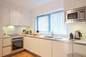 a kitchen with white cabinets and a sink and a window at Miles Place by Viridian Apartments in London