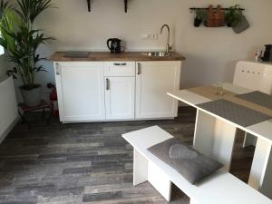 a kitchen with white cabinets and a table and a sink at Ferienwohnung Freiburg und March in Holzhausen