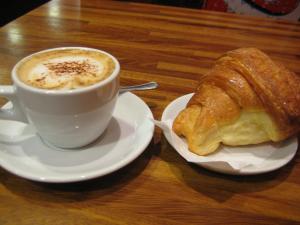 a cup of coffee and a croissant on a table at La Torre Storica in Bitonto