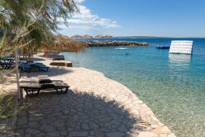 a beach with a bench and chairs in the water at Holiday Park Mandrice in Mandre