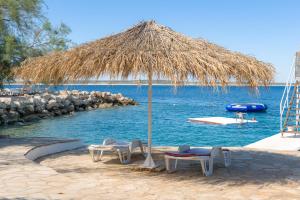 a beach with a straw umbrella and chairs and the water at Holiday Park Mandrice in Mandre