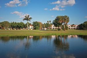 un étang en face d'un parcours de golf avec des palmiers et des maisons dans l'établissement Grand Palms Spa & Golf Resort, à Pembroke Pines