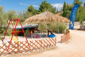 a playground with a boat and a straw umbrella at Holiday Park Mandrice in Mandre