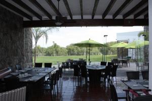 un comedor con mesas, sillas y sombrillas en Hotel Villa Mexicana Golf & Equestrian Resort, en Villa del Pueblito