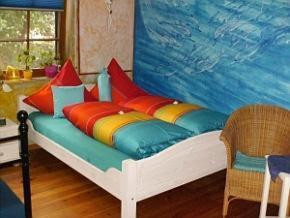 a bed with colorful pillows on it in a room at Haus Silbermond in Rust