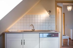 a kitchen with white cabinets and a sink and a staircase at Bellevue Ferienwohnungen in Quedlinburg +29 photos